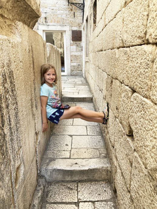 Child pressing back into one wall, feet to the other to show narrow walkway
