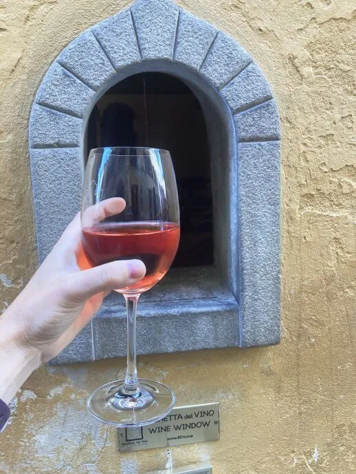 Holding a wine glass in front of a wine window in Florence Italy
