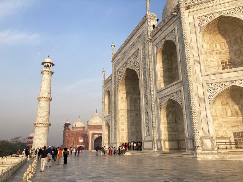 Line of people who are very small entering the large door to the Taj Mahal mausoleum
