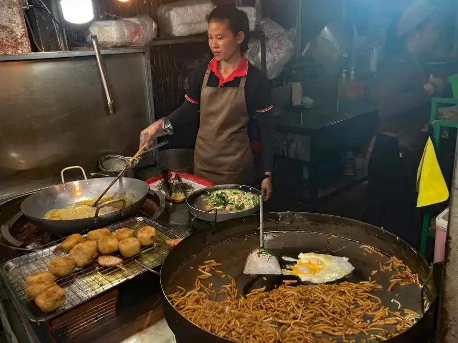 Woman cooking traditional Khmer food on a grill, street food tour of Siem Reap Cambodia