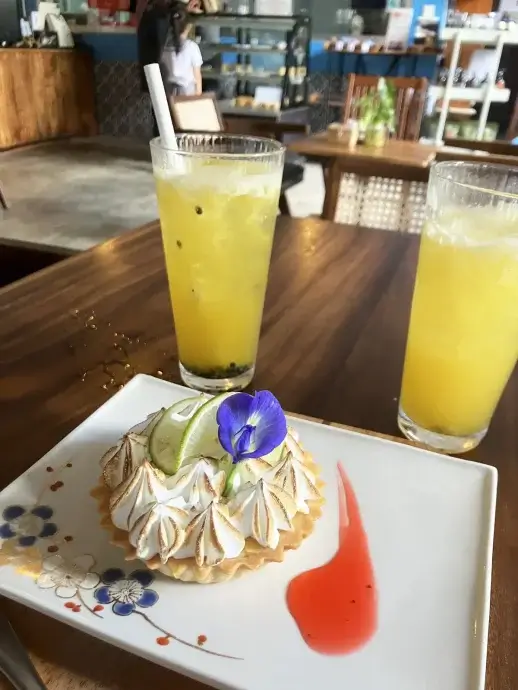 A fancy key lime tart on a plate with two tall juice glasses behind at Bayon Pastry School Cafe in Siem Reap