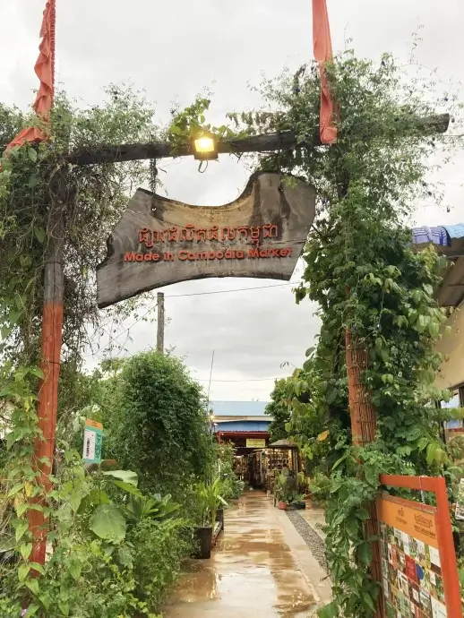 Orange posts and rough wooden sign for the Made in Cambodia Market on a rainy day in Siem Reap
