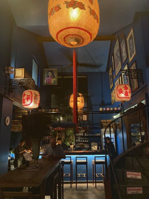 Large glowing golden lantern and the dark blue and wood interior of Miss Wong Cocktail bar in Siem Reap