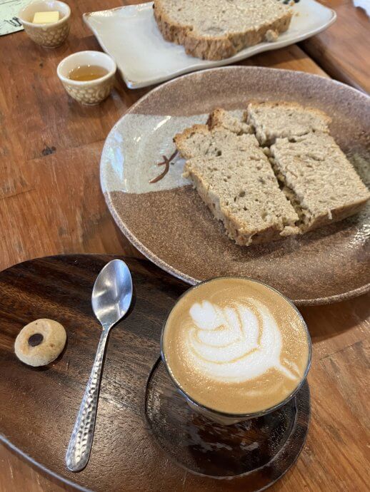 A flat white coffee and slice of banana bread on a pottery plate at Sister Srey Cafe in Siem Reap